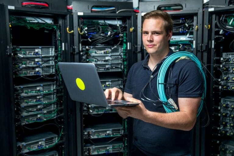 IT Professionals - an open letter - IT worker on laptop in front of data stack